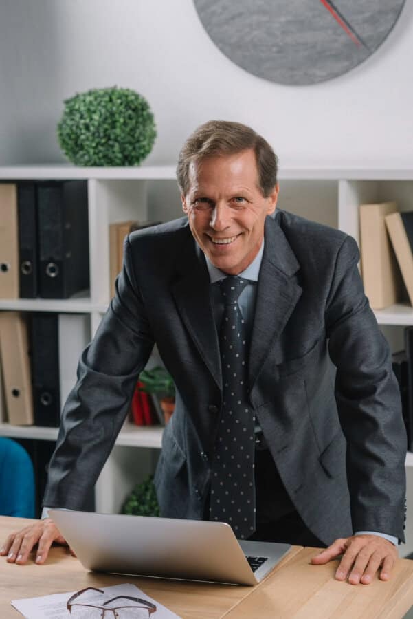 Businessman in an office standing over a laptop.